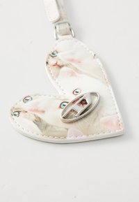 Heart-shaped keychain made of white synthetic material with a glossy surface, featuring a printed design of cats and a silver metal clasp.