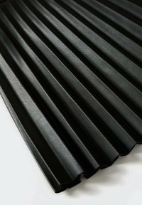 Matériau noir plissé avec une surface texturée, présentant des plis verticaux et des bords lisses. Le design met en avant la profondeur et la dimension.
