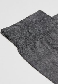 Grå strikket stof med en glat tekstur, der har en foldet manchet øverst og en sømløs overgang til hoveddelen.