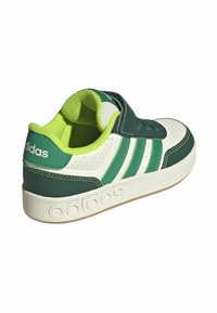 Sneaker Adidas verde e bianco con cinturino in Velcro, tomaia in pelle texturizzata, design a tre strisce e suola in gomma.
