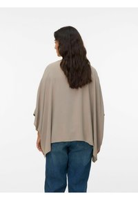 Beige kimono-stil top med brede ærmer, tekstureret stof og en løs pasform, parret med blå jeans. Udsigt fra bagsiden.