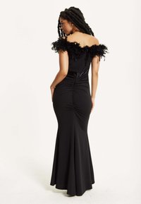 Black evening gown with an off-the-shoulder feathered neckline, fitted bodice, and flared skirt, featuring ruched detailing at the back.