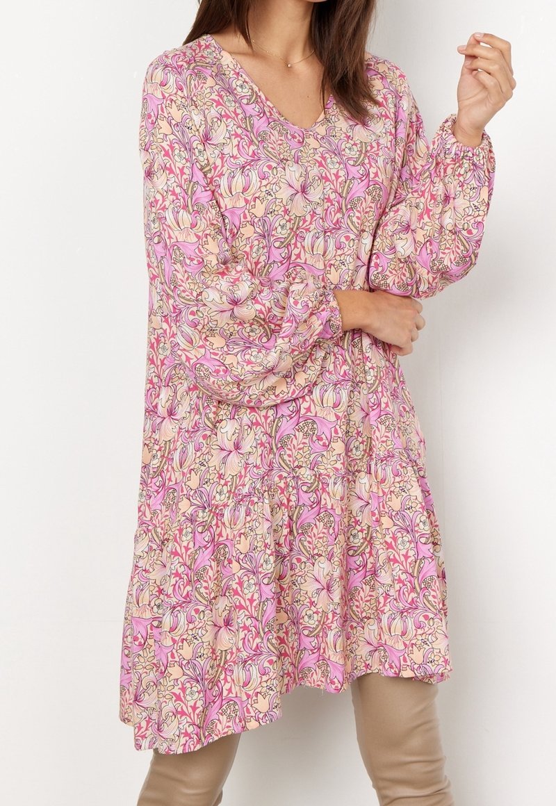 Robe à motif floral avec un col en V et des manches longues, dans des tons rose et crème. Design fluide avec un détail froncé à la taille.