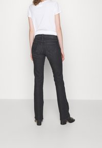 Mörk tvättade denim flarejeans med bakfickor, en mjuk textur och midja i normalhöjd, kombinerat med en enkel vit t-shirt.