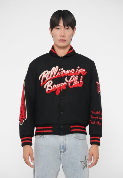 Zwarte varsityjack met rood geborduurd logo en tekst, gestreepte ribgebreide manchetten, knoopsluiting en gemusterde accenten op de mouwen.