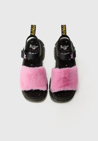 Svart sandaler med en bred rosa kunstpelsrem, justerbar svart spenne, og en gul "AirWair" trekkebånd på hælen. Teksturert gummisåle.