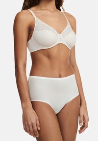 Weißer Spitzen-BH mit weichen Cups und dünnen Trägern, kombiniert mit hochgeschnittenen weißen Panties, die eine glatte Textur und ein einfaches Design aufweisen.