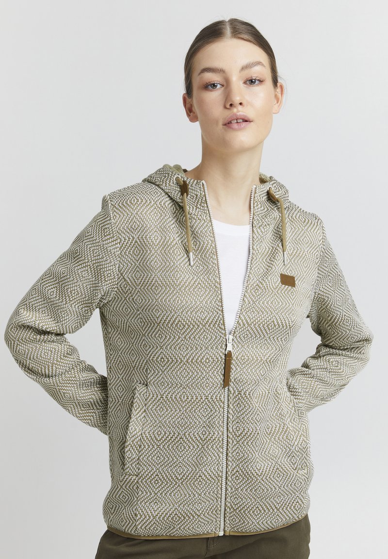 Veste à capuche zippée en tissu à motifs beige et crème, avec deux poches avant et des accents à cordon.