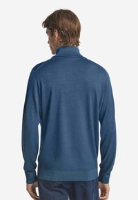 Dunkelblauer Pullover mit hohem Kragen, langen Ärmeln, gerippten Bündchen und glatter Textur. Verfügt über eine lockere Passform und ein minimalistisches Design.