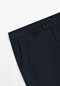Marinblå skräddarsydda byxor i slät tyg, med dragkedja, knappstängning, sidofickor och rena sömnadsdetaljer.