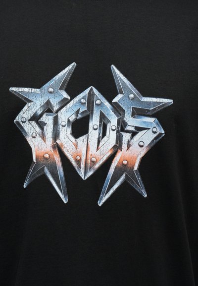 Μεταλλικό ασημί και πορτοκαλί φθαρμένο κείμενο "ACDC" με διακοσμητικά σε σχήμα αστεριού σε μαύρο ύφασμα.