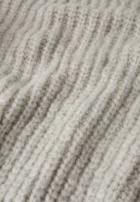 Vaaleanharmaa neulottu kangas, jossa pystysuora ribbineulos, pehmeä ja pörröinen pinta sekä hienovaraiset paksuusvaihtelut.