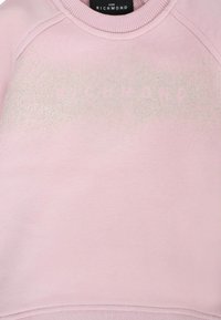 Jasnoróżowa bluza z miękkiego materiału, z teksturową powierzchnią i subtelnym, błyszczącym napisem "RICHMOND" z przodu.