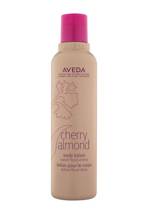 Flacon de lotion pour le corps Aveda Cherry Almond avec un bouchon rose, un motif de feuille florale, et texte décrivant un arôme floral doux en anglais et en français.