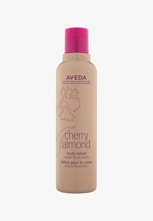 Flacon de lotion pour le corps Aveda Cherry Almond avec un bouchon rose, un motif de feuille florale, et texte décrivant un arôme floral doux en anglais et en français.