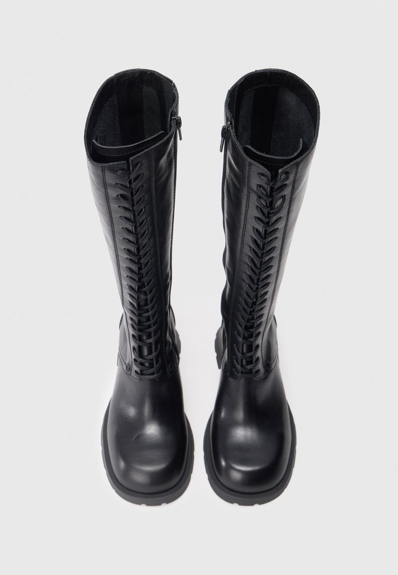Sorte læderstøvler til knæet med et struktureret, snøret design langs siderne og lynlåse bagpå, med en chunky gummisål.