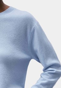 Jasnoniebieski sweter wykonany z miękkiego dzianiny. Posiada okrągły dekolt, długie rękawy oraz luźny krój z subtelną teksturą.