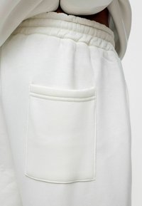 Witte katoenen trainingsbroek met een zachte textuur, met een gerimpelde tailleband en een vierkante zak op één kant.