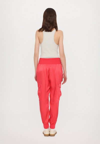 Lichtgrijs tanktop en levendig roze cargo broek, met elastische tailleband en enkelmanchetten, inclusief zijzakken voor extra functionaliteit.