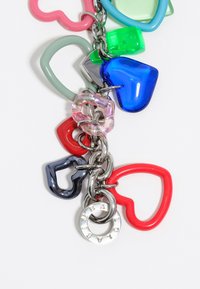 Encantos de plástico coloridos en forma de corazón en rojo, azul, verde y rosa, enlazados por cadenas de metal plateado brillante. Incluye un acento circular de plata.