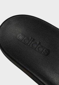 Černé skládací sandály Adidas s texturovaným svrchním materiálem a embosovaným logem. Zakřivený tvar a hladké hrany nabízejí minimalistický design.