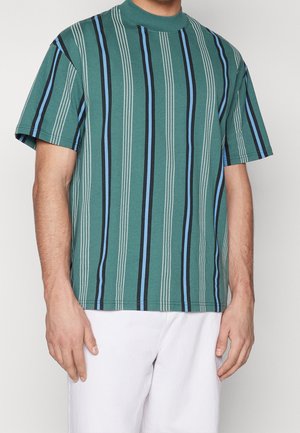 Koszula krótki rękaw w kolorze teal, z pionowymi paskami w kolorze czarnym i niebieskim, wykonana z miękkiej tkaniny z okrągłym dekoltem i luźnym krojem.