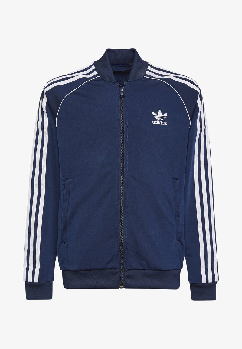 Tmavě modrá zipová bunda se bílými pruhy na rukávech, vyrobená z hladkého materiálu, s vyšitém logem Adidas na hrudi.