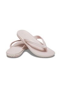 Tongs rose clair en plastique souple avec une surface texturée, dotées d'un lit de pied moulé et de semelles blanches. Marque Crocs présente.