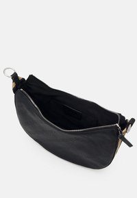 Borsa a zip nera realizzata in materiale testurizzato, con un ampio interno rivestito in nero e una tracolla esterna in color nocciola.