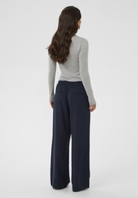 Gray long-sleeve top paired with navy wide-leg trousers featuring an elastic waistband and two back pockets, viewed from the back.