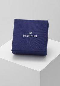 Námornícky modrá textúrovaná šperkovnica s magnetickým uzáverom, na prednej strane s bielym logom Swarovski a emblémom labute.