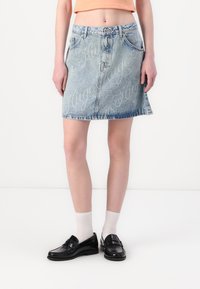 Gonna di jeans in azzurro chiaro con un lavaggio sbiadito e un motivo ripetuto "Hugo". Presenta una vita aderente, tasche laterali e un orlo svasato.