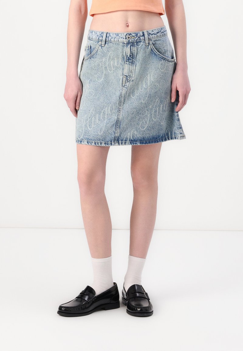 Gonna di jeans in azzurro chiaro con un lavaggio sbiadito e un motivo ripetuto "Hugo". Presenta una vita aderente, tasche laterali e un orlo svasato.