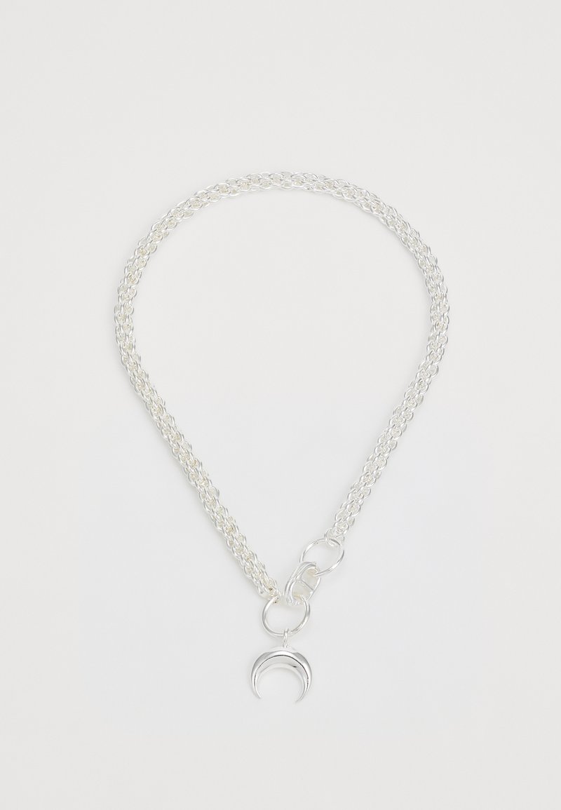 Hõbedane ahel, millel on põimunud lingid ja kuu moodi ripats. Lihtne klõpsuga sulgemine sulandub disaini.