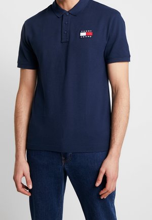 Mörkblå polo t-shirt i bomull, med tvåknäppt fram, korta ärmar och en liten broderad logotyp med röda och vita accenter.