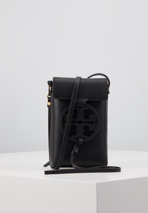 Zwarte leren crossbodytas met klepsluiting, ronde uitsnede logo aan de voorkant en een lange verstelbare riem, tentoongesteld op een witte ondergrond.