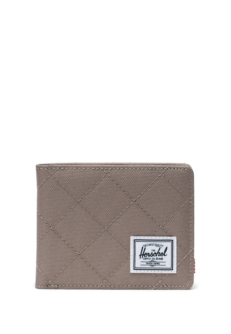 Cartera acolchada gris con forma rectangular, presenta una etiqueta blanca con texto negro y costura roja en el lateral. Textura de tela resistente.