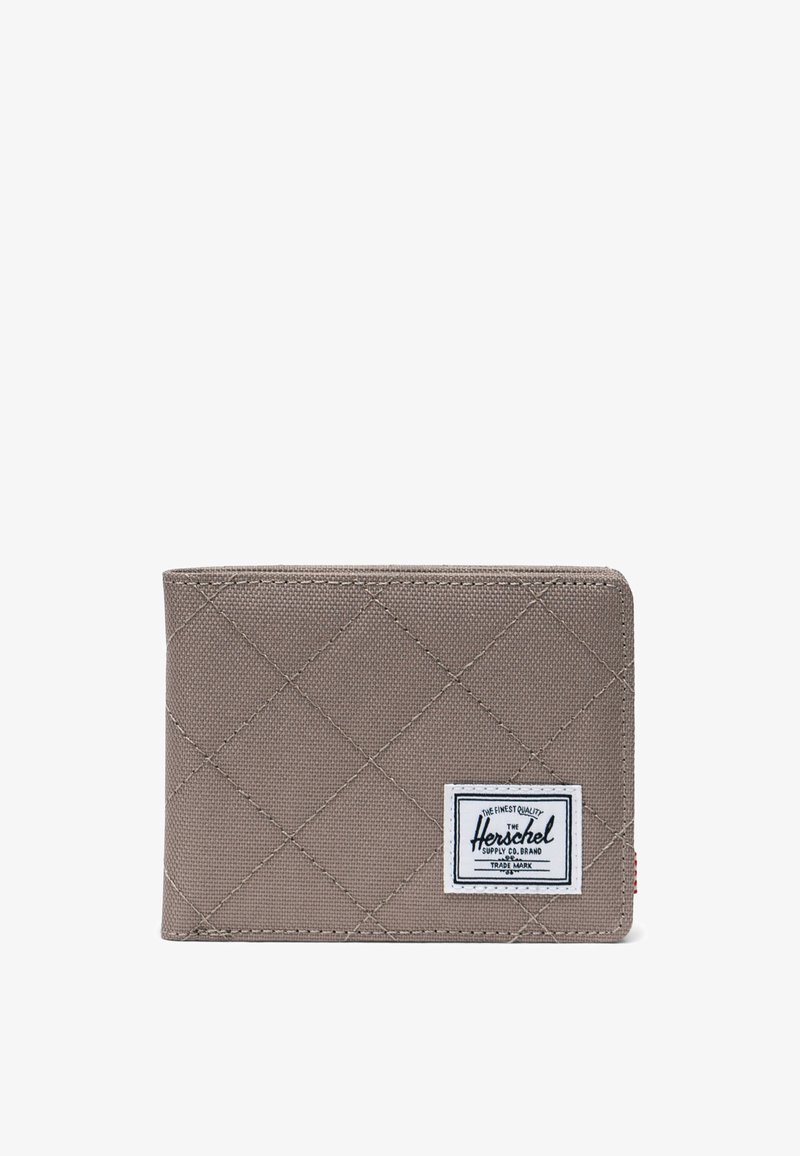 Cartera acolchada gris con forma rectangular, presenta una etiqueta blanca con texto negro y costura roja en el lateral. Textura de tela resistente.