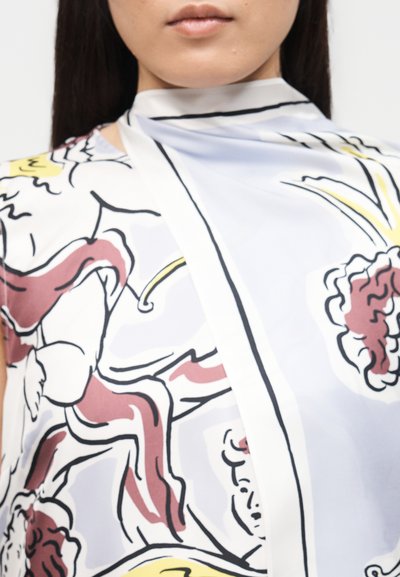 Κοντινό πλάνο ενός ατόμου που φοράει μεταξωτό μαντήλι με αφηρημένα λουλουδένια σχέδια σε λευκό, μπορντό, κίτρινο και μαύρο χρώμα.