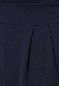 Tecido plissado azul marinho com um acabamento texturizado e uma faixa larga na cintura. Foco nos detalhes das pregas para adicionar forma e estilo.