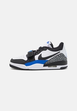 Baskets noires, blanches et bleues avec une tige en cuir et mesh, un bout perforé et des accents de motif éléphant sur le talon.