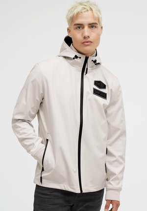 Light beige hooded jacket made of smooth material, featuring black zipper and patches. Long sleeves with cuff details and side pockets.