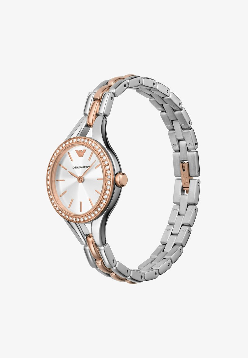 Montre en métal argent et or rose avec un cadran rond, une lunette en forme de diamant et un bracelet articulé. Elle présente un cadran blanc et de simples marqueurs d'heure.
