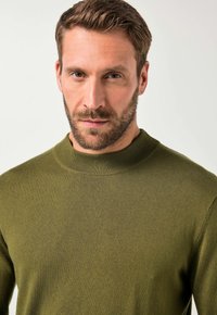 Olivgrüner Pullover mit hohem Rippkragen, glatter Textur und körperbetontem Design, das eine nahtlose Strickkonstruktion betont.