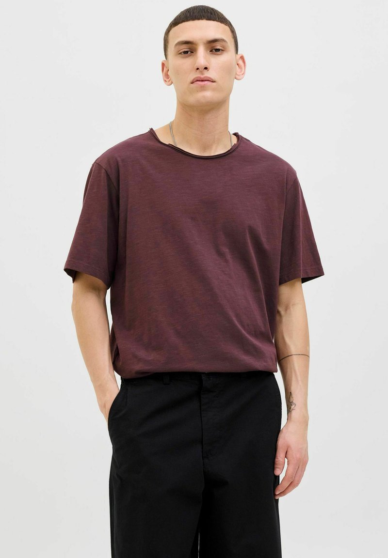 Bordó, rövid ujjú póló, laza fazonú és kerek nyakkivágású. Puha tapintás, fekete nadrággal párosítva. Minimalista design, minta nélkül.