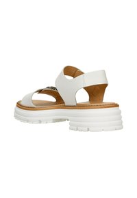 Sandale en cuir blanc avec design découpé, semelle intérieure en bois et semelle en caoutchouc blanche épaisse avec un relief texturé pour une meilleure adhérence.