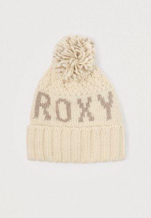 Knit beanie in cream with a ribbed cuff, featuring a textured body and a large pom-pom on top. The word "ROXY" is knitted in brown.