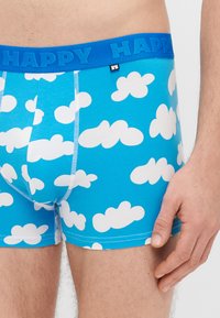 Μπλε ανδρικά εσώρουχα boxer με σχέδιο σύννεφα, ελαστική μέση με την ένδειξη «HAPPY» σε μπλε και αντίθετη λευκή ραφή.
