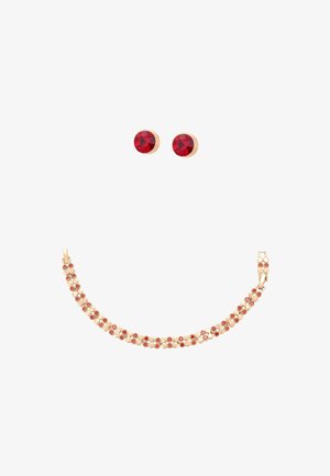 Set de brățară din aur și cercei cu tărtăcuțe asortați, cu pietre prețioase rotunde roșii, aranjate separat pe un fundal alb.
