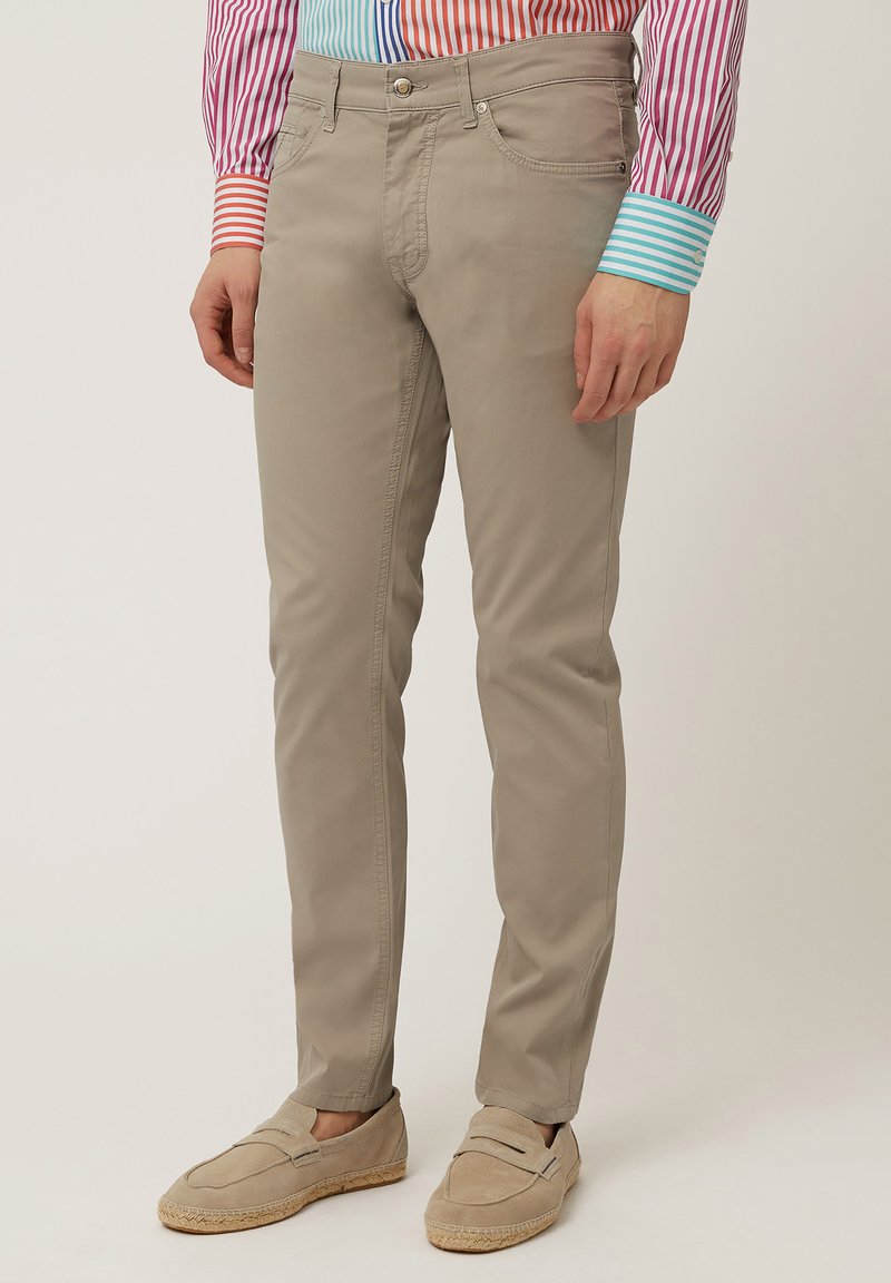 Chinos beige con un corte slim, que cuentan con bolsillos delanteros y traseros, y una mezcla de algodón suave y ligera. Complementados con mocasines de ante claros.
